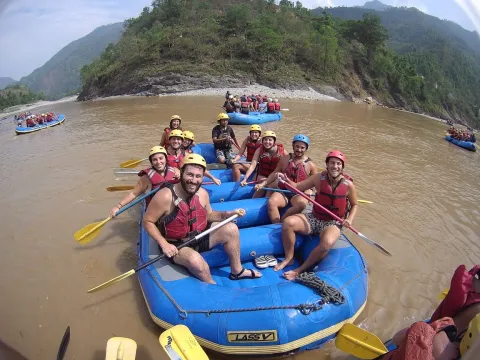Group enjoying Trishuli River rafting surrounded by green hills
