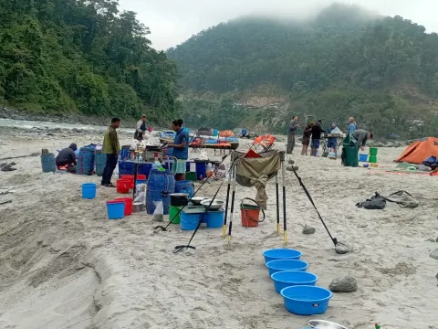 Family relaxing beside a sandy river beach during their Lower Seti adventure